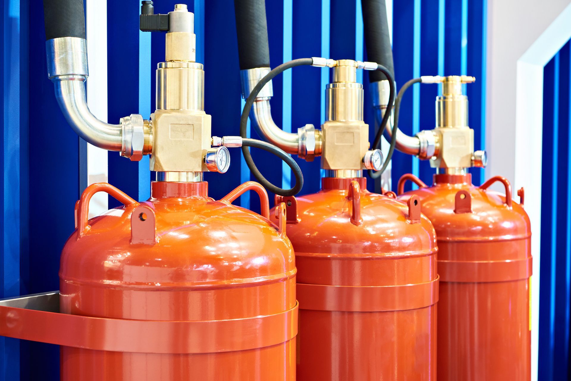 A row of fire extinguishers sitting next to each other on a wall. A row of fire extinguishers sitting next to each other on a wall.