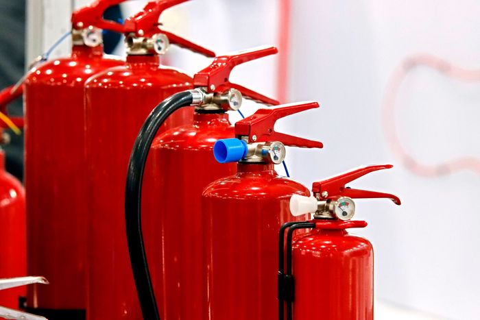 A row of red fire extinguishers are lined up in a row. A row of red fire extinguishers are lined up in a row.