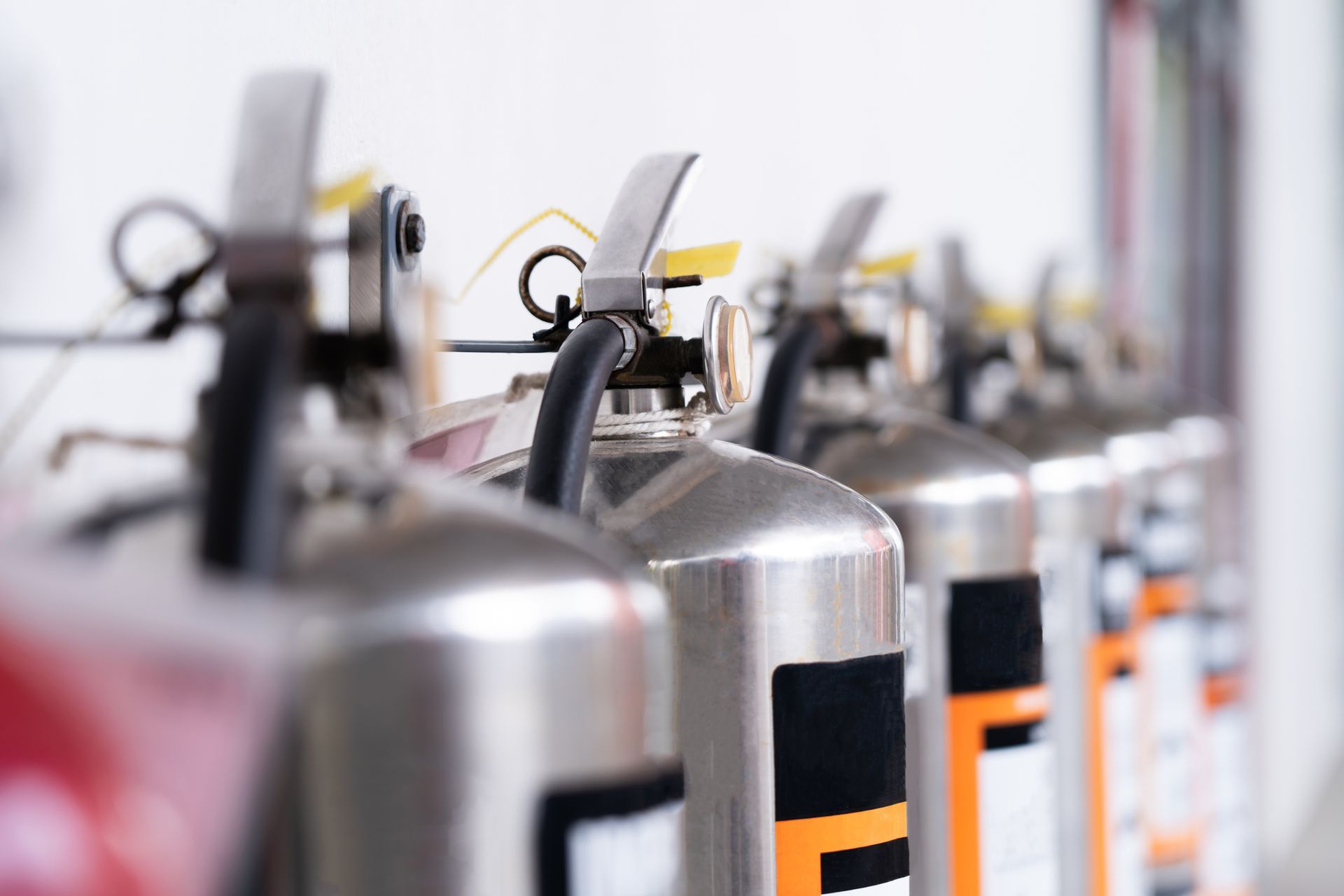 A row of fire extinguishers are lined up in a row. A row of fire extinguishers are lined up in a row.