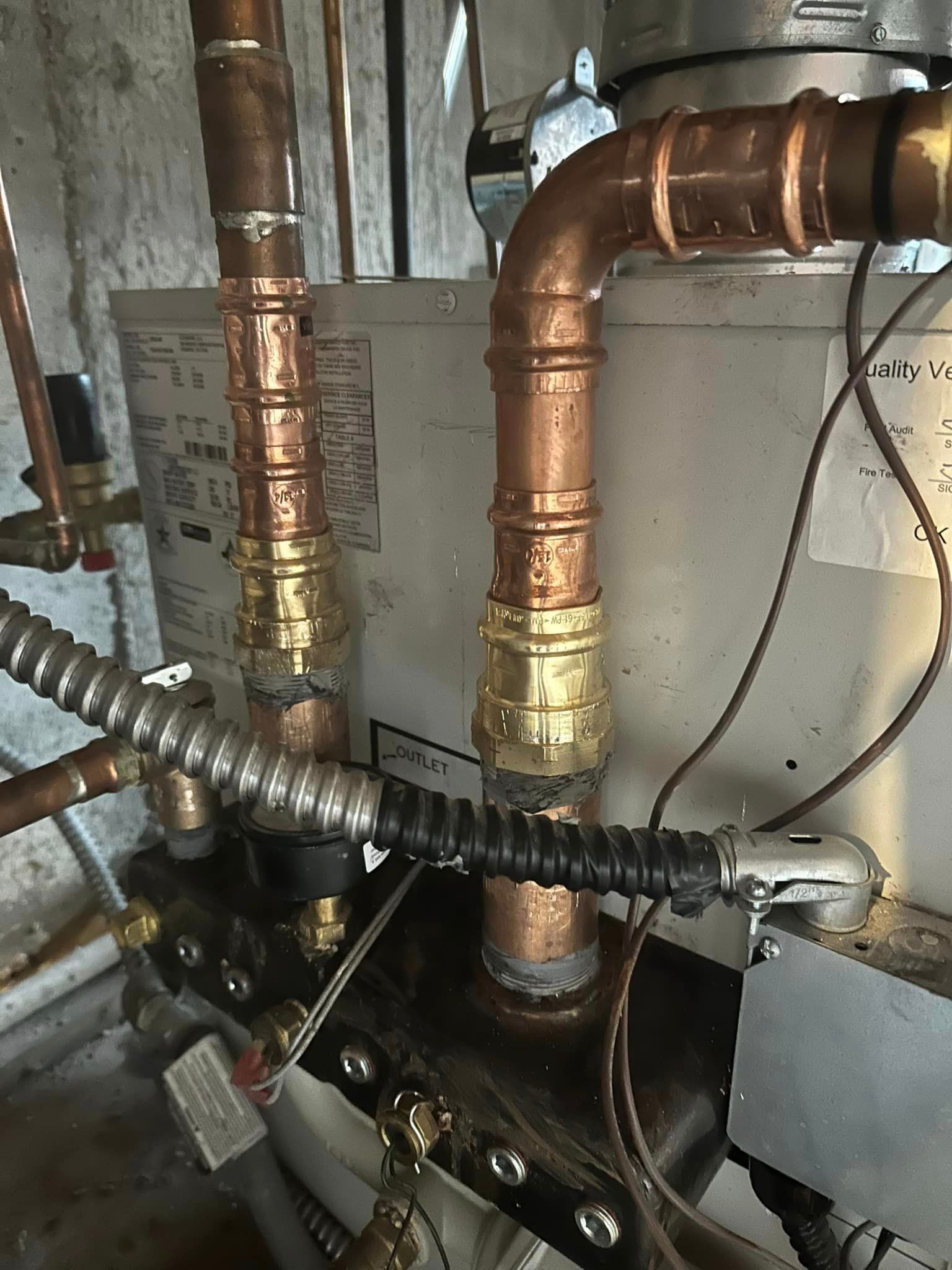 A close up of a water heater with copper pipes attached to it.