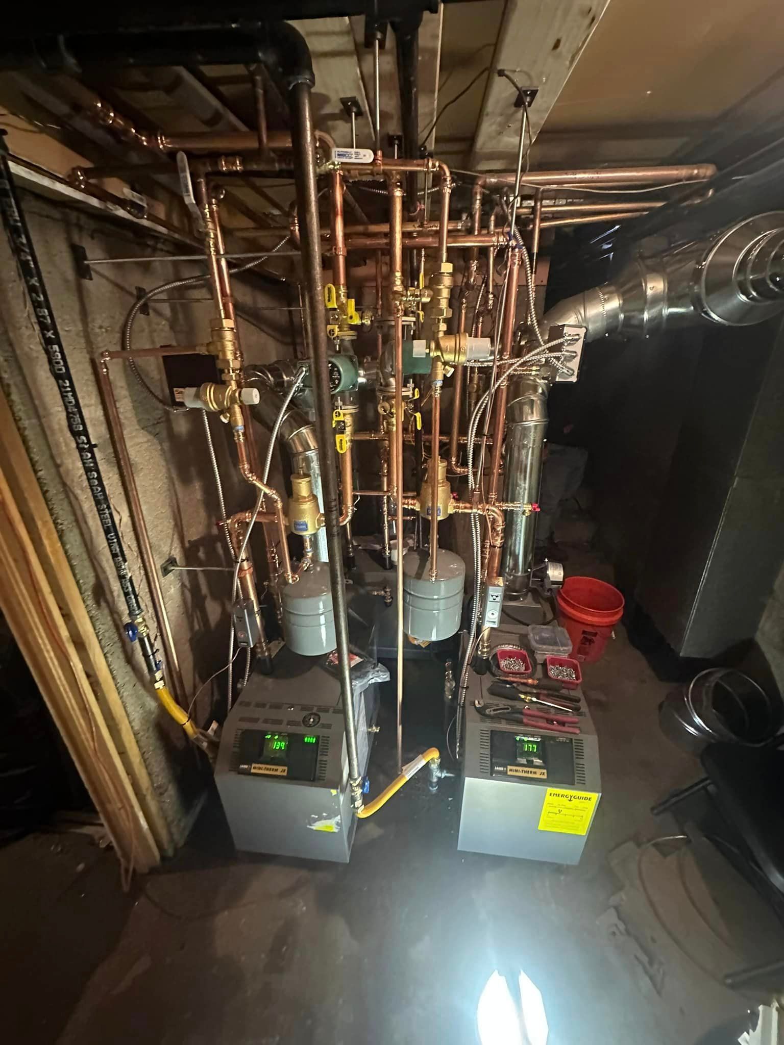 A room with a lot of pipes and heaters in it.