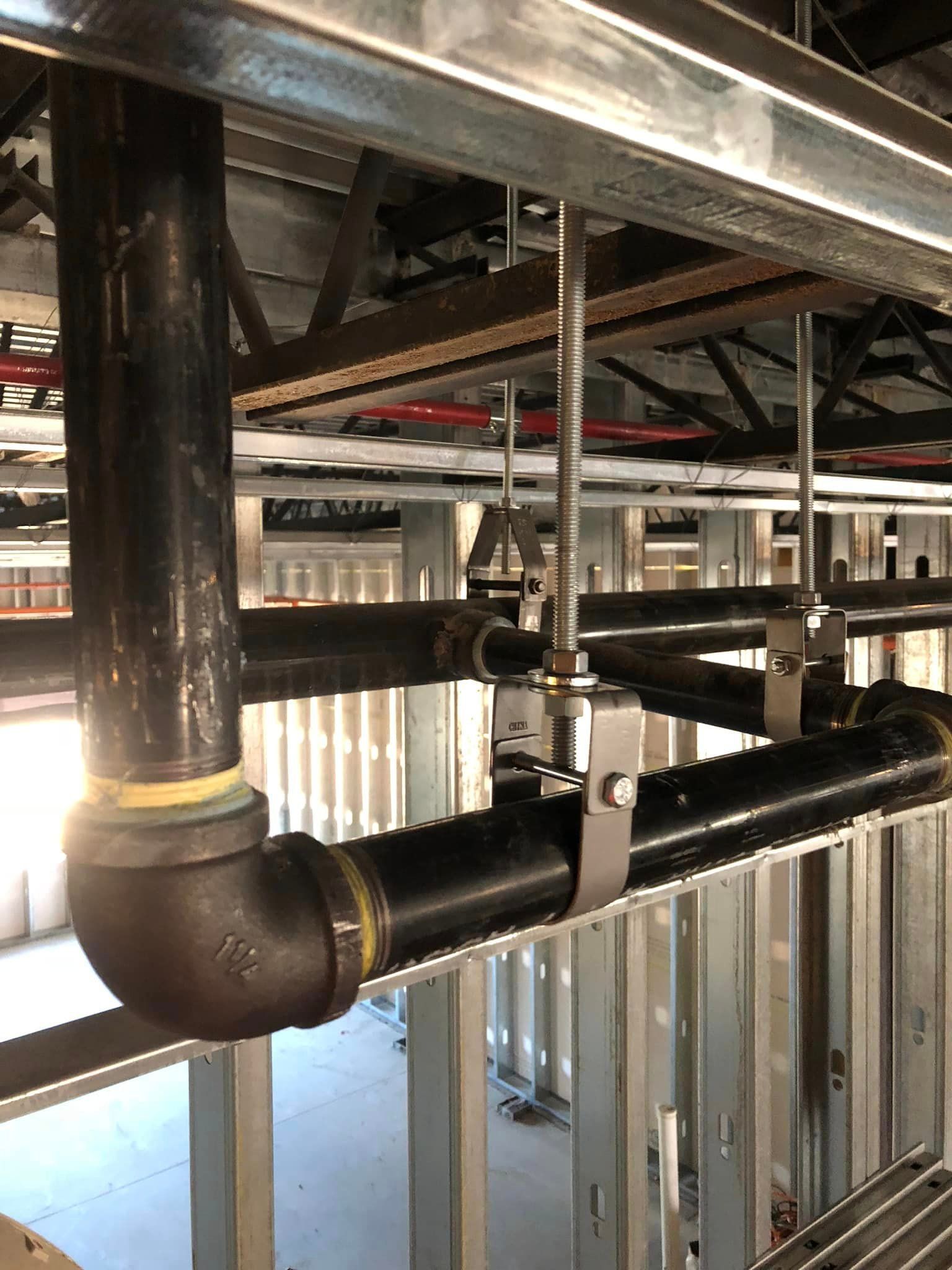 A bunch of pipes are hanging from the ceiling of a building.