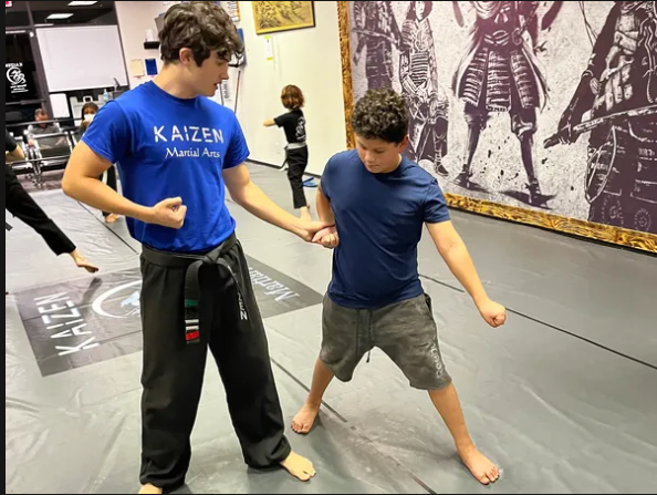 Young Champions Program student receiving instructor feedback at Kaizen Academy in Gilbert, AZ