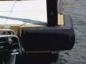 Close-up of a black dock cleat with rope on a boat by the water