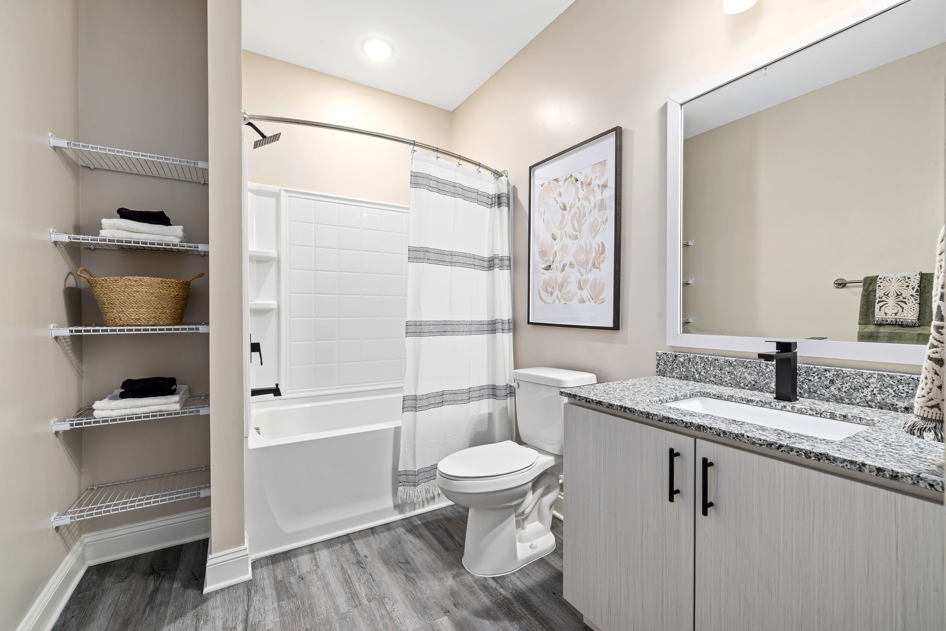 Modern bathroom with tub, toilet, granite vanity, and gray tile flooring