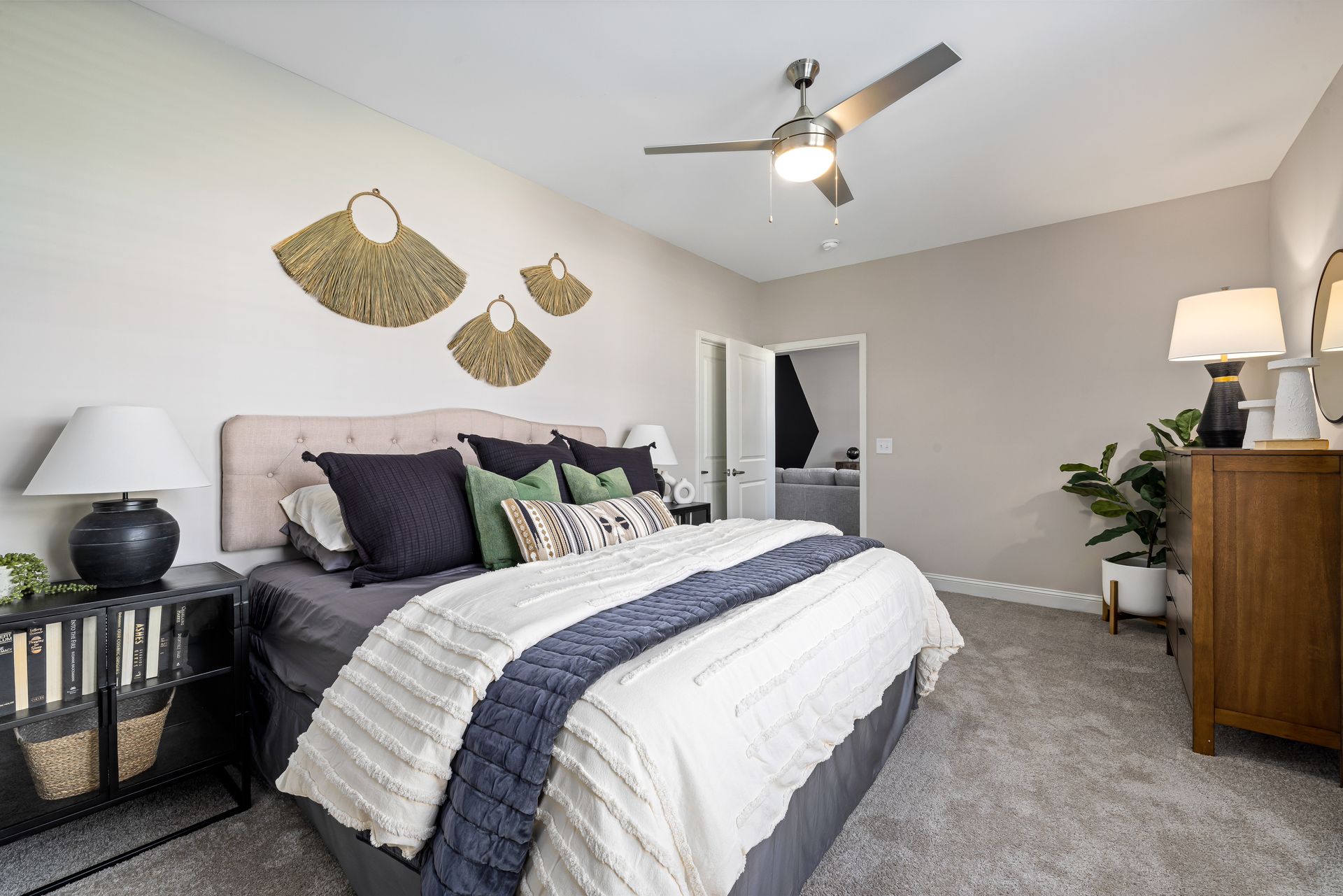 Bright bedroom with a queen bed, gray walls, ceiling fan, and woven wall decor.