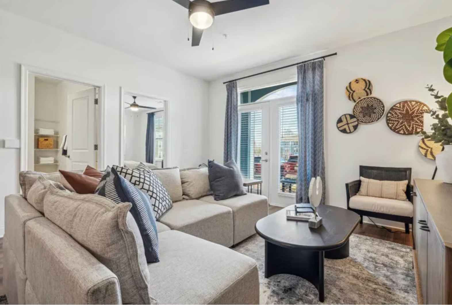 Bright living room with a beige sectional, black coffee table, wall decor, and sliding glass doors