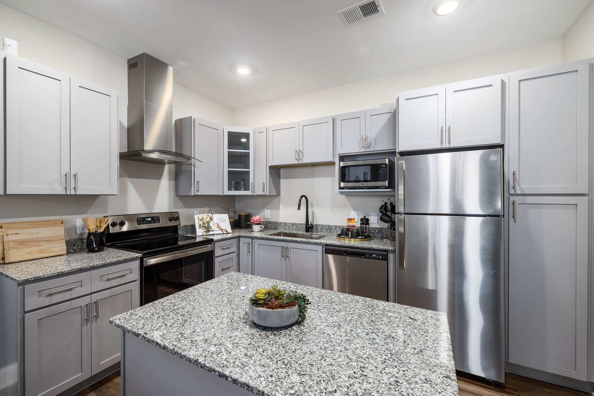 Modern gray-and-white kitchen with stainless steel appliances and a speckled island countertop