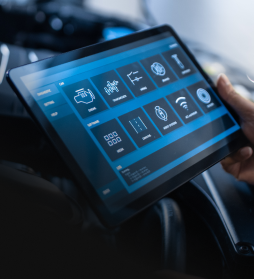Person holding a tablet with a blue car dashboard interface on screen | E&R Automotive