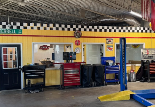 Auto shop interior with yellow walls, tool cabinets, lift, and checkered trim | E&R Automotive