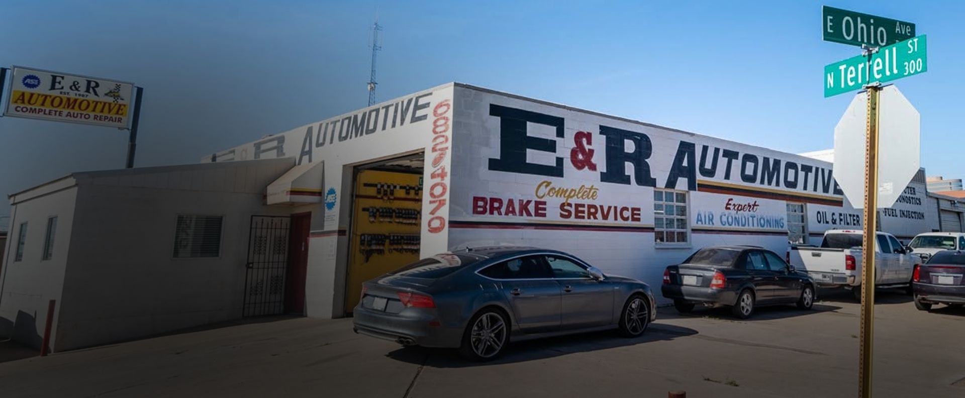 E&R Automotive brake service building with parked cars on a sunny street corner | E&R Automotive