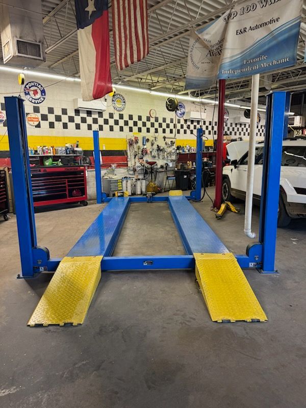 Blue auto lift with yellow ramps in a mechanic shop garage | E&R Automotive