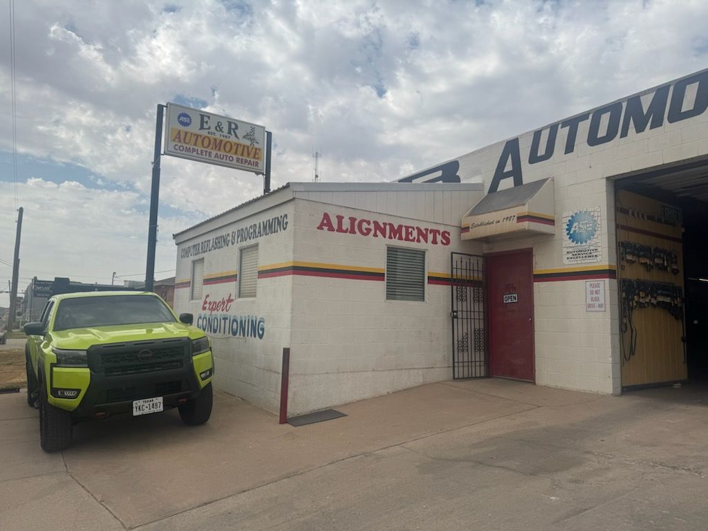 Auto alignment shop exterior with a neon-green car parked outside under cloudy skies| E&R Automotive