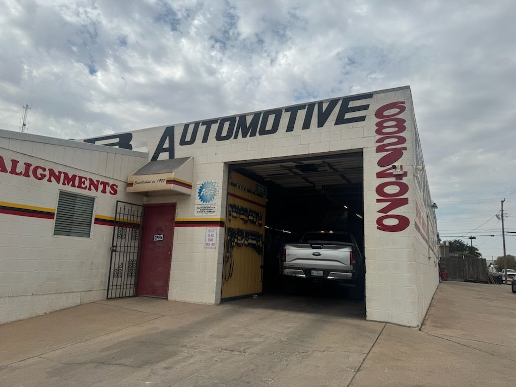 Auto repair shop exterior with a car inside the garage bay and large “Automotive” signage. | E&R Automotive