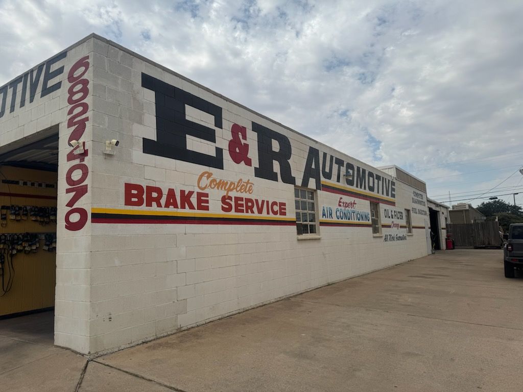 E&R Automotive brake service shop with large wall sign on a beige building under a cloudy sky | E&R Automotive