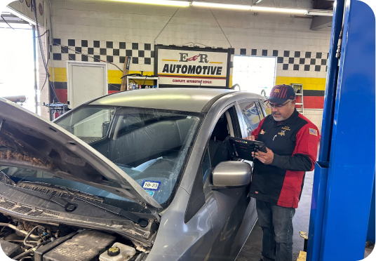 Mechanic inspecting a silver car in an auto repair shop with hood open | E&R Automotive