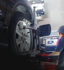 Car wheel being aligned in a repair shop with a technician using a computer monitor | E&R Automotive