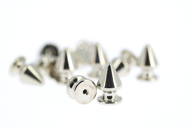 Un gioielliere utilizza un utensile rotante con un piccolo disco lucidante per rifinire un anello di diamanti tenuto in una morsa metallica.