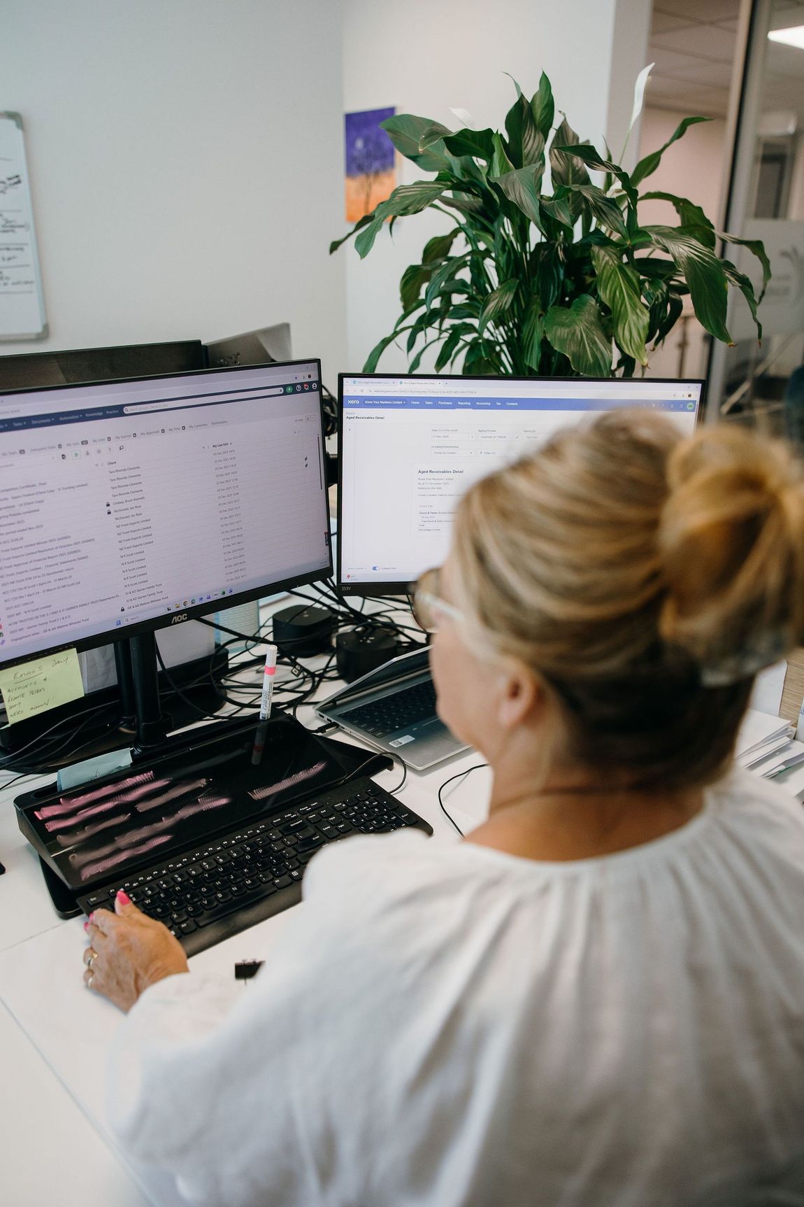 Person working at dual computer monitors in an office workspace