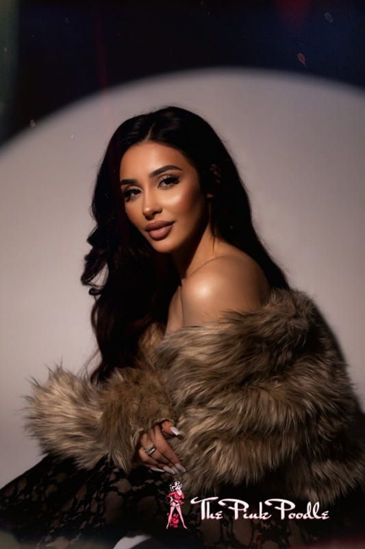 Portrait of a woman in a fur coat, posing against a soft white backdrop with dramatic lighting