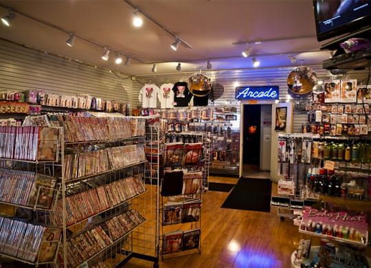 Cluttered arcade shop interior with shelves of games, souvenirs, and a neon “Arcade” sign