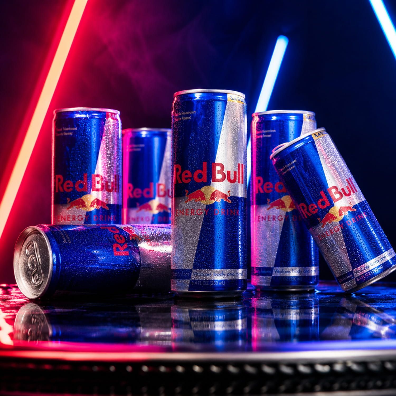 Red Bull energy drink cans in metallic blue and red neon lighting on a reflective surface