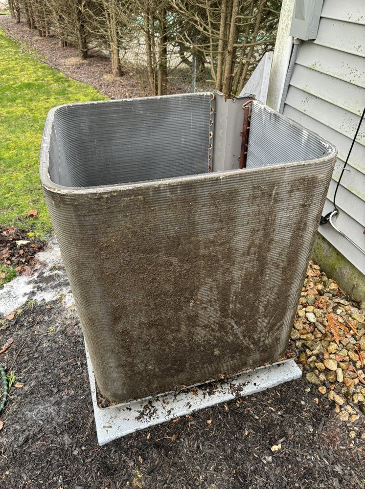 Outdoor air conditioning unit covered in dirt and debris, next to a building.