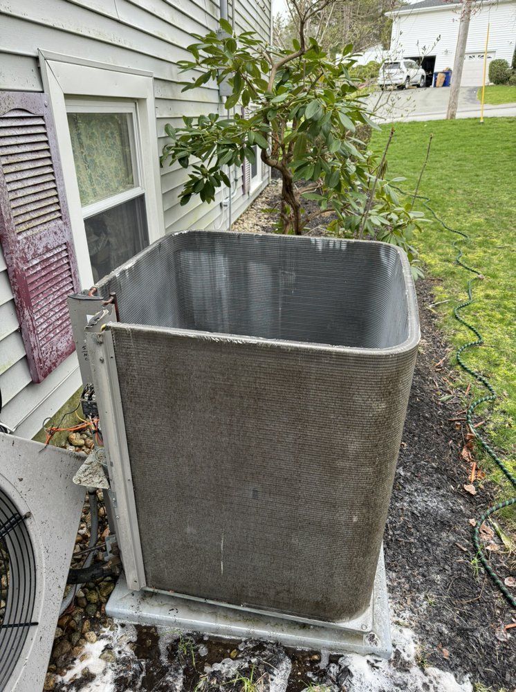 An outdoor air conditioning unit with the top half removed sits next to a house.