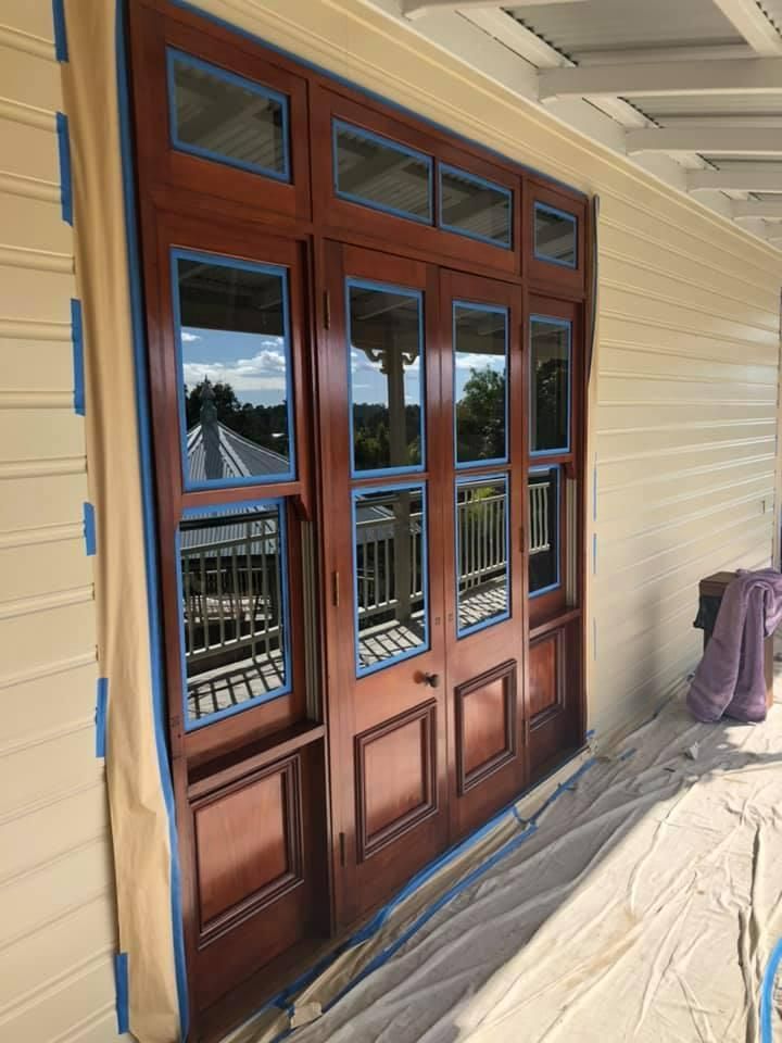 A Wooden Door with Blue Tape on It Is Being Painted on A Porch — Allman's Painting in Monkland, QLD