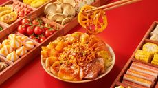Red festive snack display with assorted pastries and a bowl of orange-glazed dessert topped with chopsticks