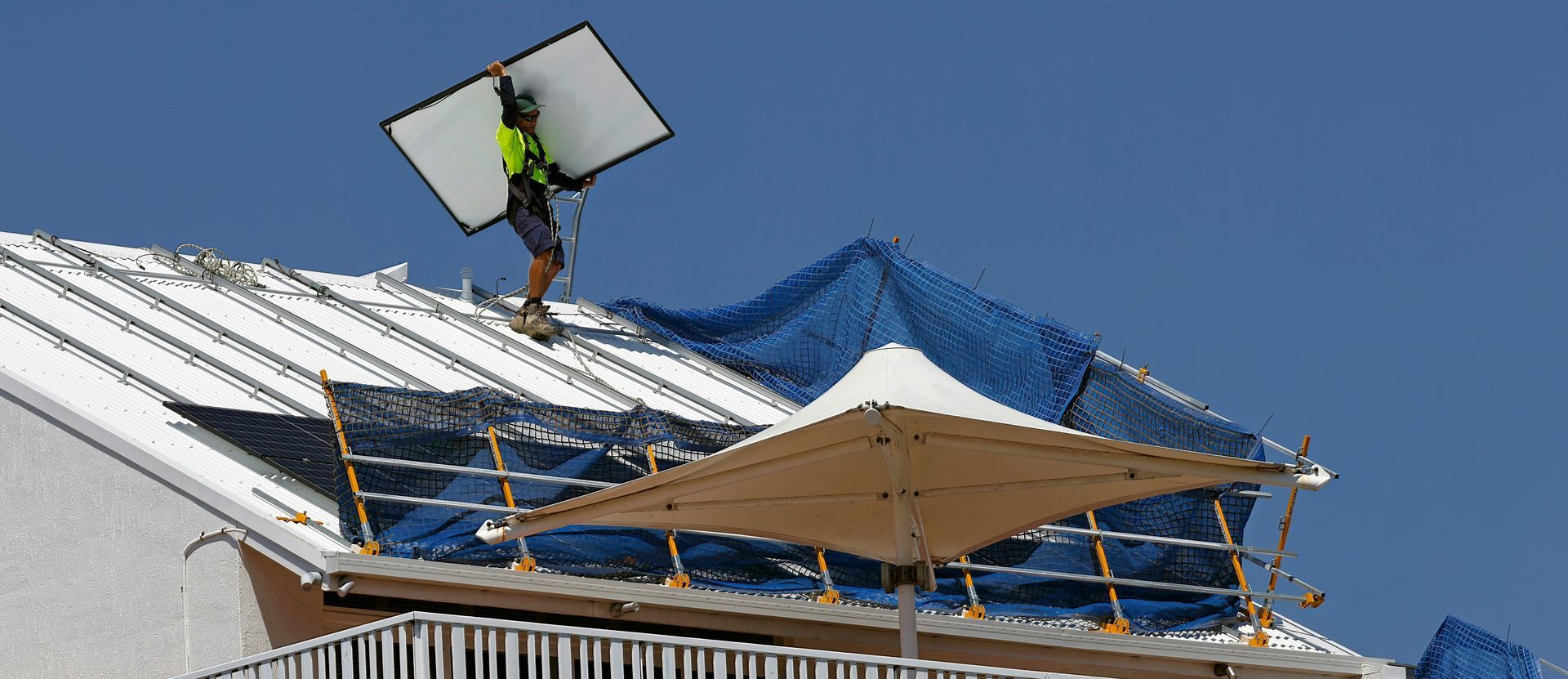 A professional installing solar panels on a roof, showing the expertise and safety standards needed to qualify as an ACT builder.