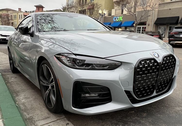 Silver BMW sedan parked on a city street, front three-quarter view