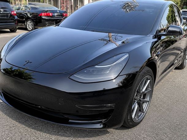 Black Tesla sedan parked outdoors with tinted windows and glossy finish