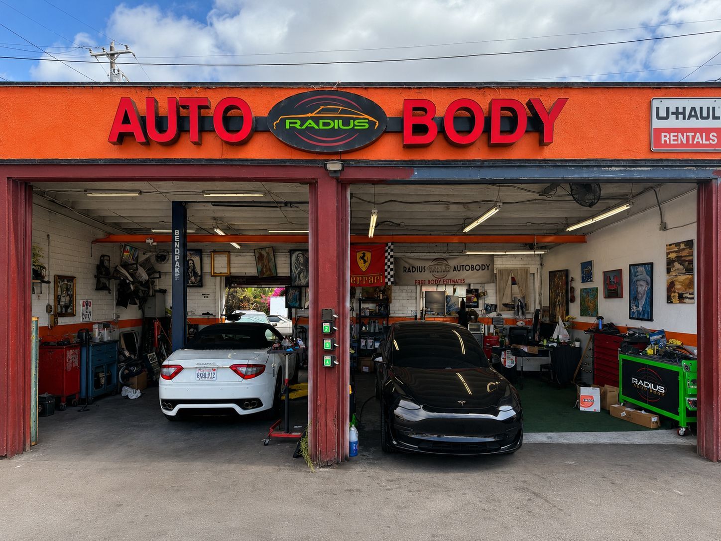 Auto body shop storefront with two cars parked in open service bays