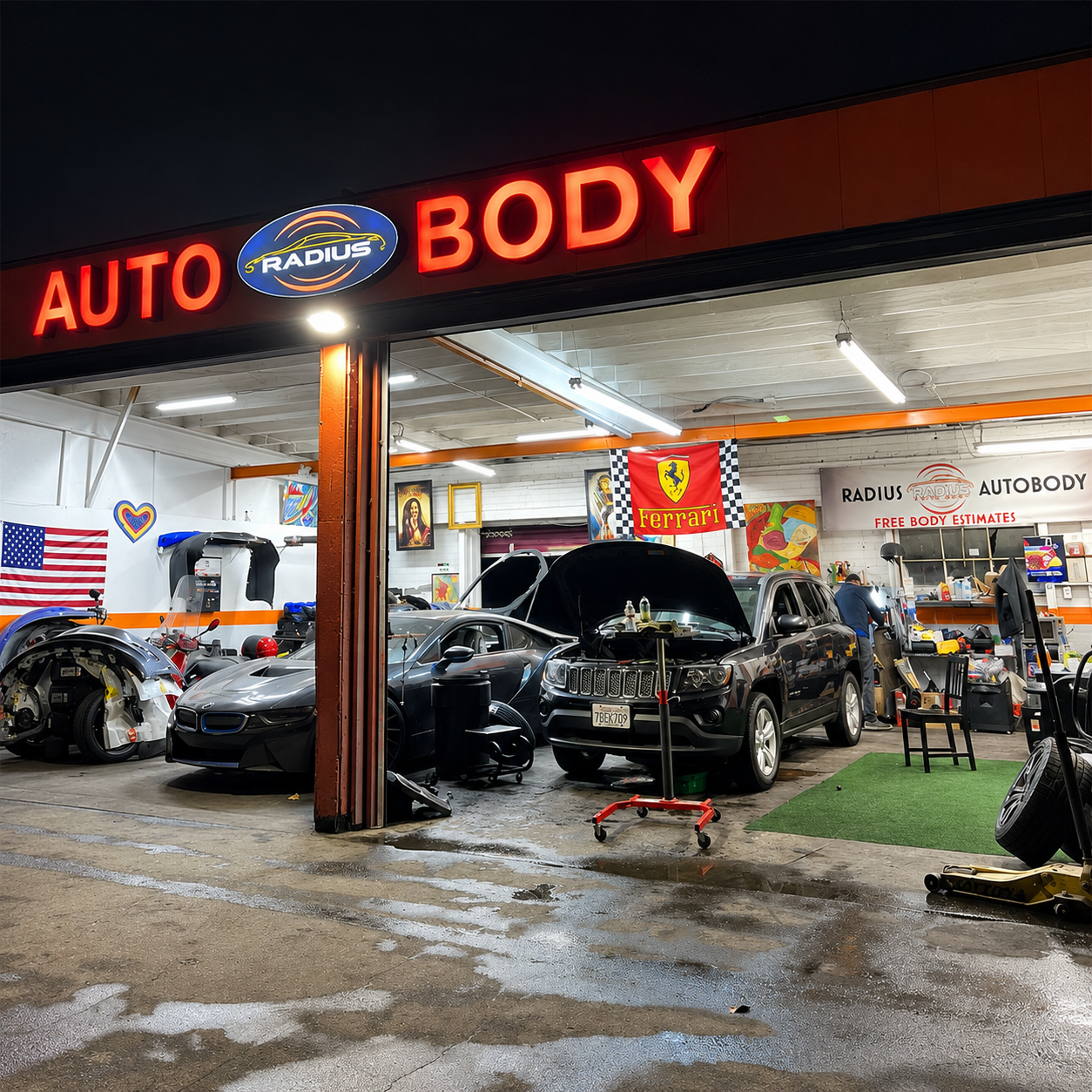 Auto body shop at night with cars under repair, neon sign glowing, and flags on the wall.