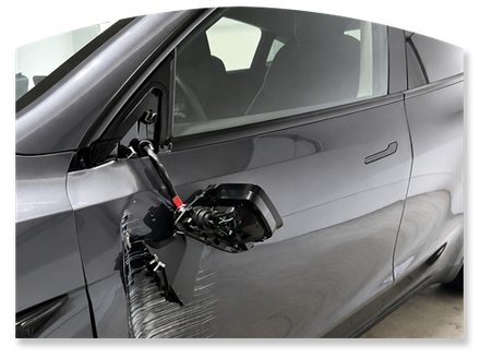 Damaged black car side mirror hanging off a silver car door