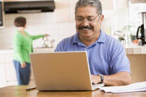 man on laptop while wife is in the background