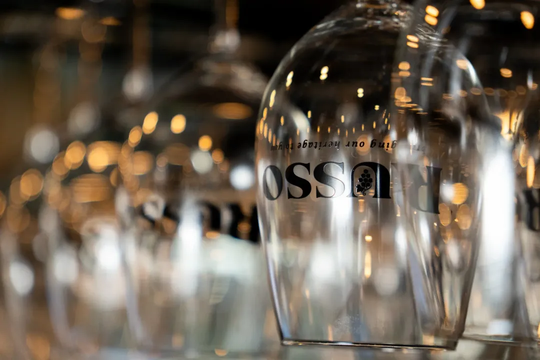 Row of wine glasses, the closest one with the logo "OSSO" in black.