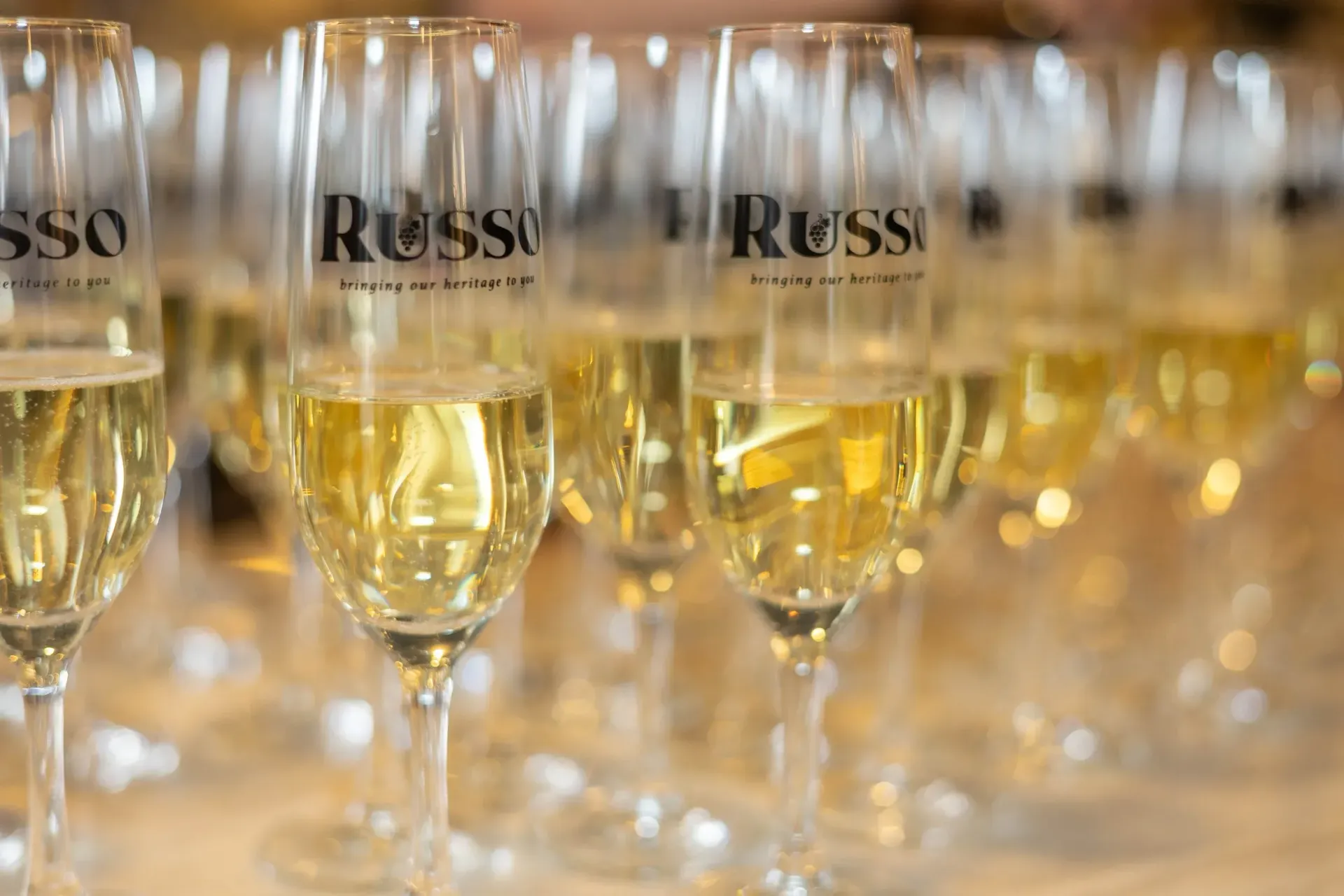 Rows of champagne glasses filled with sparkling wine, logo 