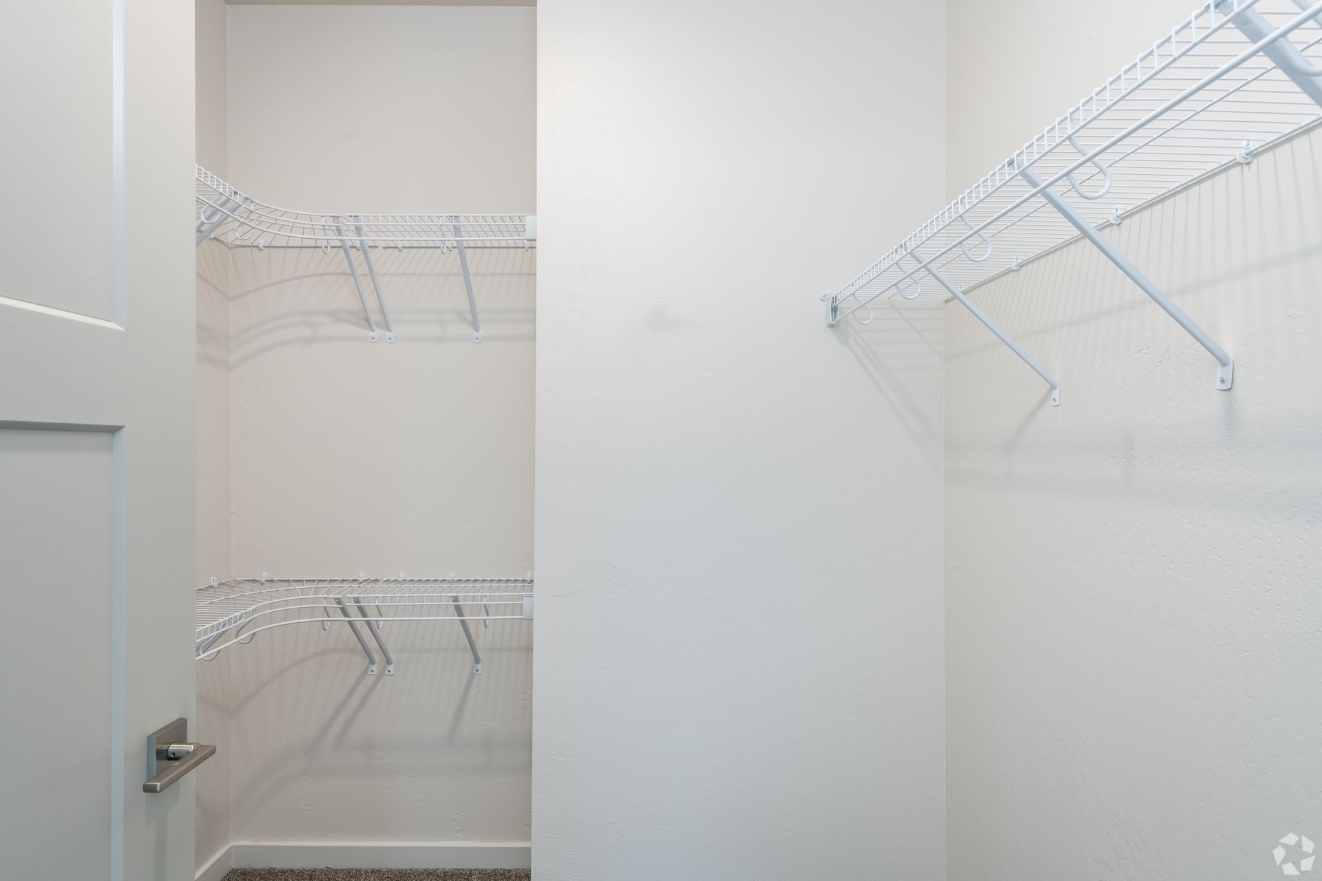 Empty white closet with wire shelving on the walls and door open
