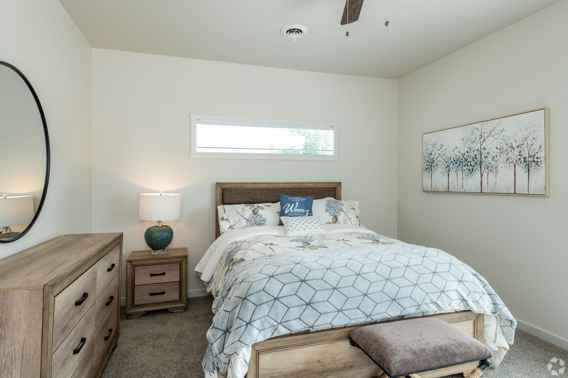 Bright bedroom with a bed, nightstands, dresser, and wall art in neutral tones