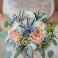 Bridal bouquet with peach, white, and blue flowers, greenery, and eucalyptus leaves