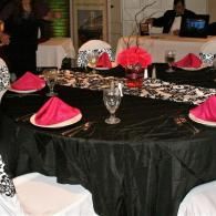Round banquet table with black tablecloth, red napkins, and decorative centerpieces in a reception hall