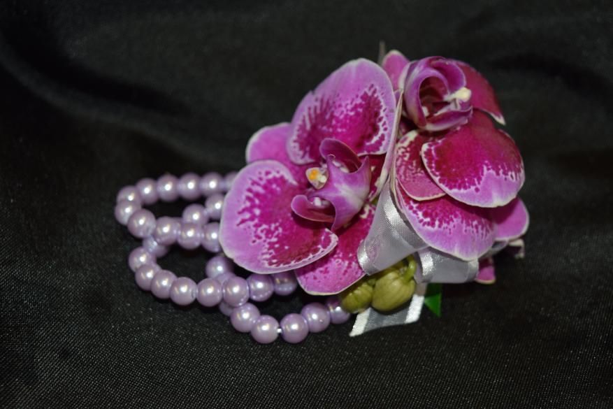 Pink orchid corsage with pearl beads on a black background