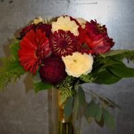 Red, white, and burgundy flowers arranged in a bouquet against a gray background