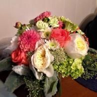 Mixed bouquet of pink, white, and green flowers in a vase on a table