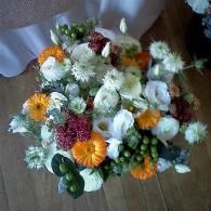 Mixed bouquet of white, orange, and red flowers on a wooden table