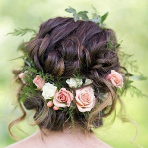 Braided updo adorned with pink and white roses and greenery
