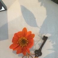 Orange flower and black keychain on a light patterned surface