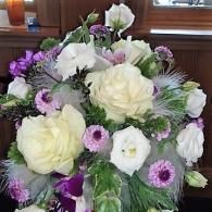 White and purple floral bouquet with roses and daisies in a vase